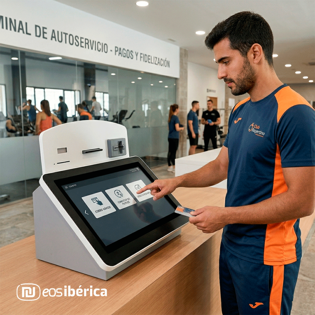 Un hombre con uniforme deportivo utiliza un quiosco de autoservicio para pagos y fidelización en la recepción de un gimnasio.